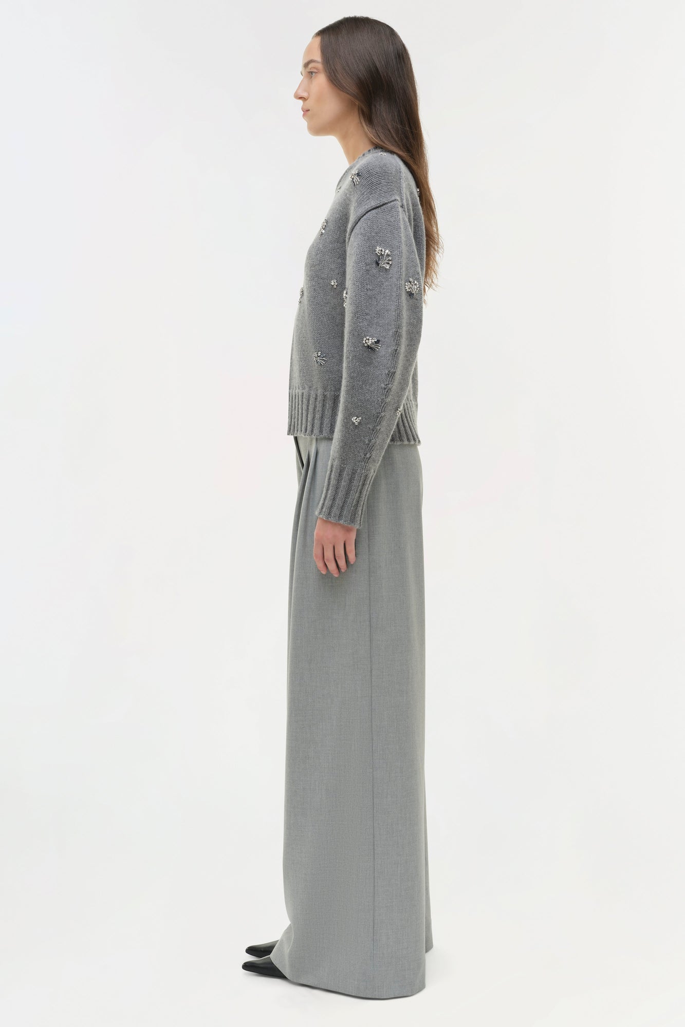 Gray knit crewneck sweater with scattered crystal embellishments worn with matching long skirt.