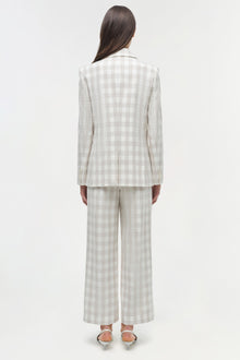 Woman wearing a cream and white gingham double breasted blazer with matching wide-leg trousers, shown from back.