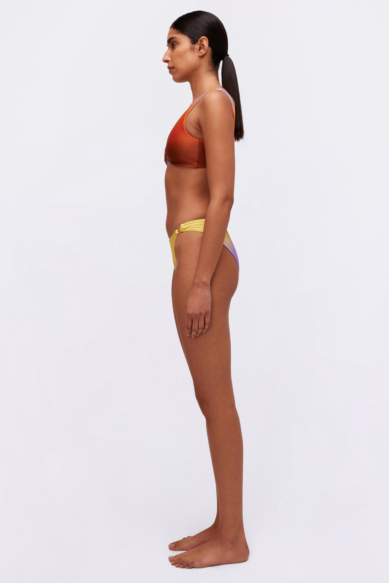 Yellow and purple colorblock bikini bottom with side tie details, shown in profile view.