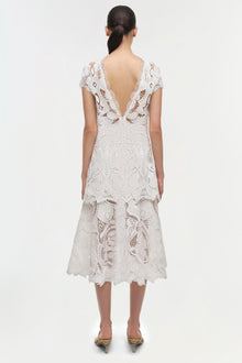 White lace midi dress with short sleeves, open back, and tiered skirt, shown on model from behind.