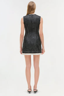 Black jacquard sleeveless mini dress with white trim at hem, shown on model from back.