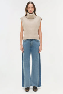 Woman wearing blue straight leg jeans with a cream turtleneck sleeveless sweater and leopard print platform shoes.