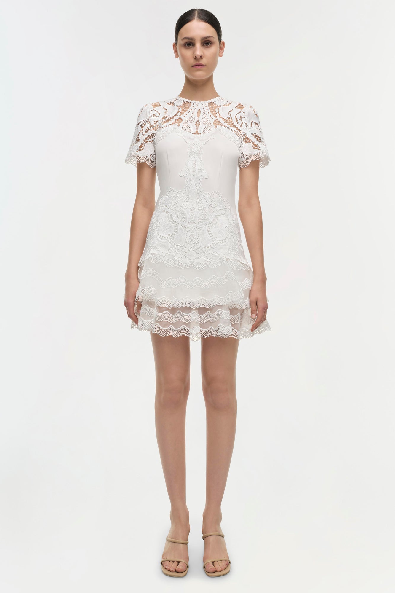 White lace dress with short sleeves, paisley patterned bodice, and tiered lace skirt.