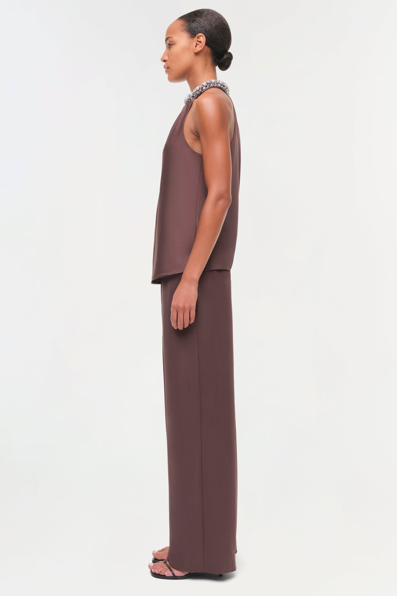 Brown satin sleeveless top with crystal embellished neckline, worn with matching wide-leg pants.