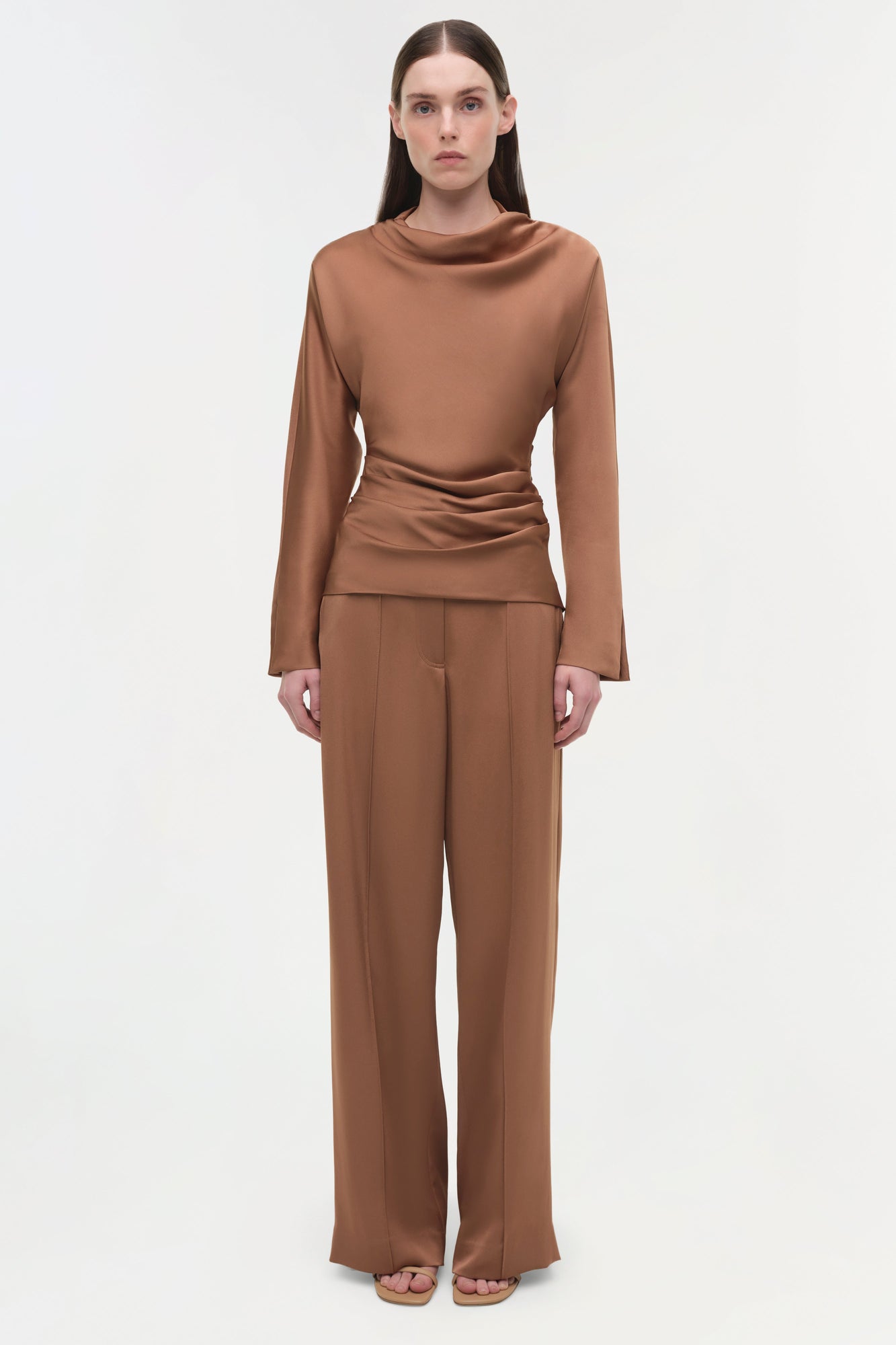 Woman wearing camel-colored satin wide-leg pants with a matching long-sleeve cowl neck top.