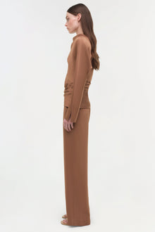 Brown satin draped top with long sleeves worn with matching floor-length skirt, shown from side profile.