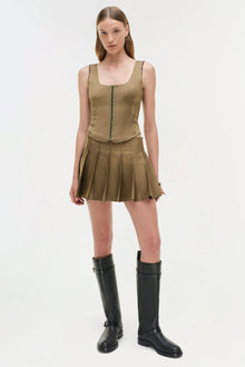 Tan sleeveless bustier top with center front zip and matching pleated mini skirt, styled with black knee-high boots.