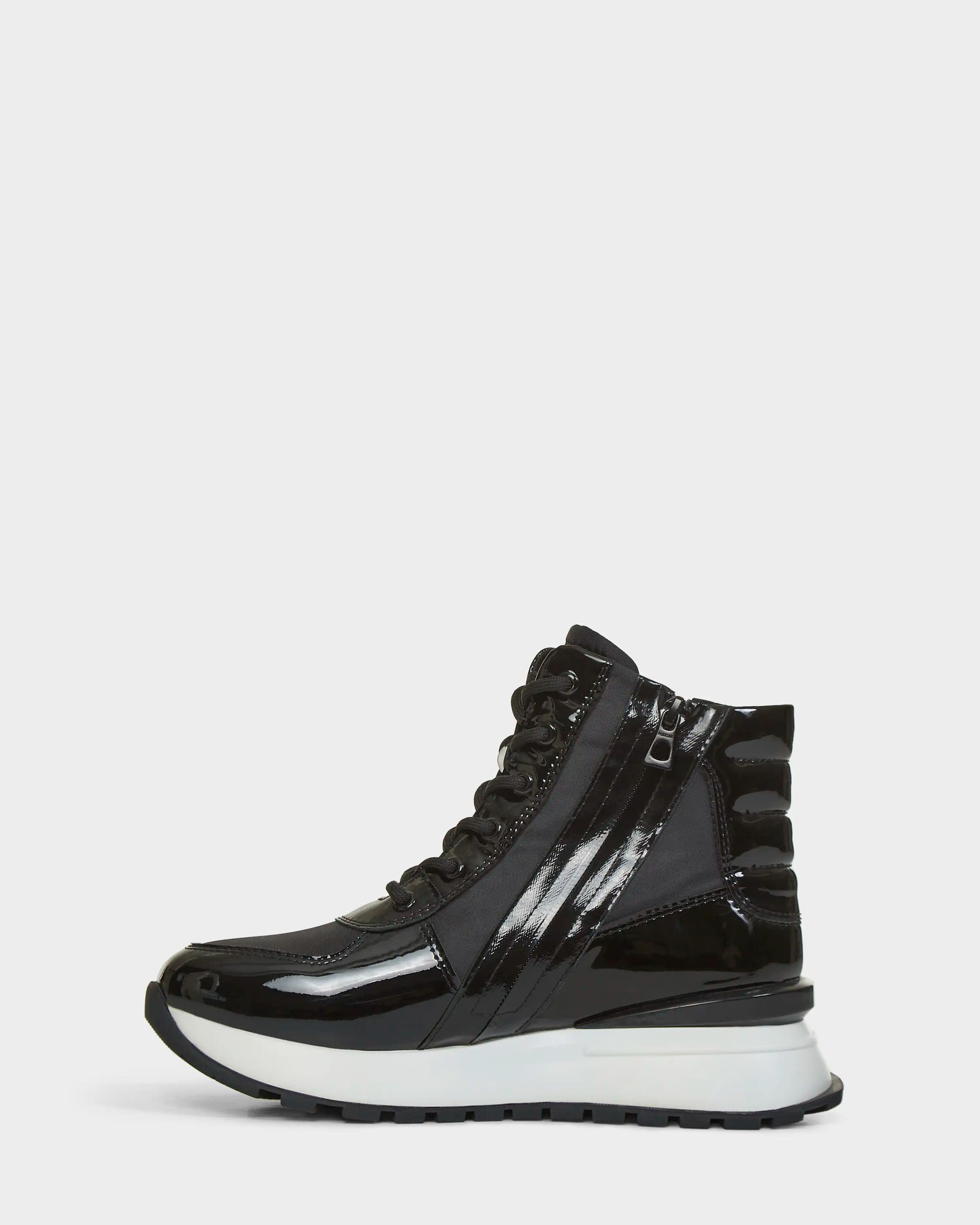 The Rudsak CHELSA - L223505 Black is a black patent leather high-top sneaker with black laces, a side zipper, and a thick white and black sole, displayed from the side on a plain white background.