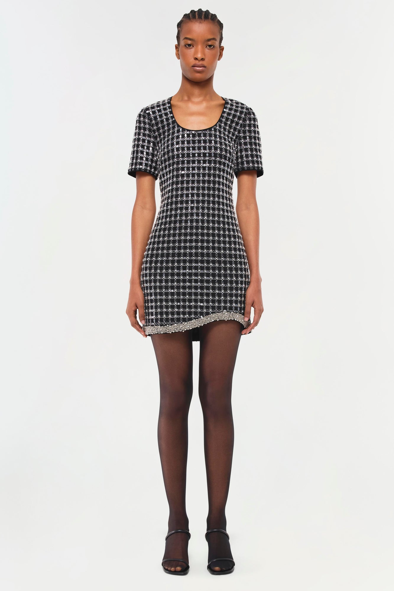 Black and white geometric patterned short-sleeve dress with beaded hem trim worn with dark tights.