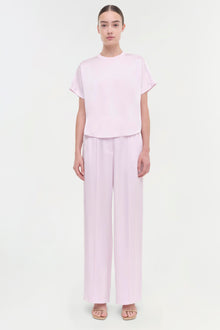 Woman wearing light pink short-sleeve t-shirt and matching wide-leg pants with slide sandals.