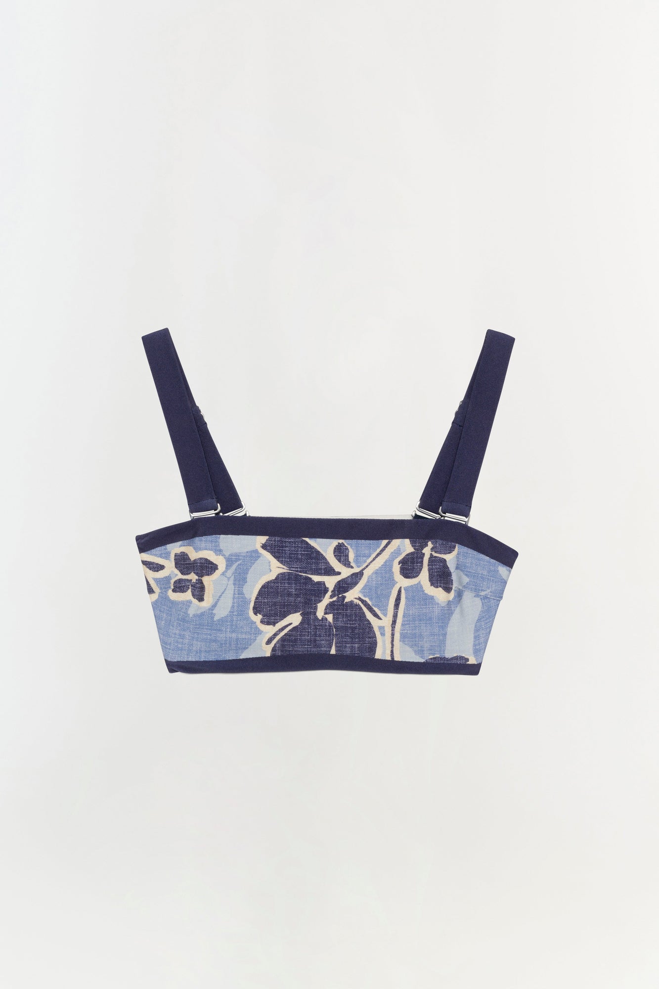 Blue bikini top with navy floral print, dark trim, and adjustable shoulder straps with metal hardware.