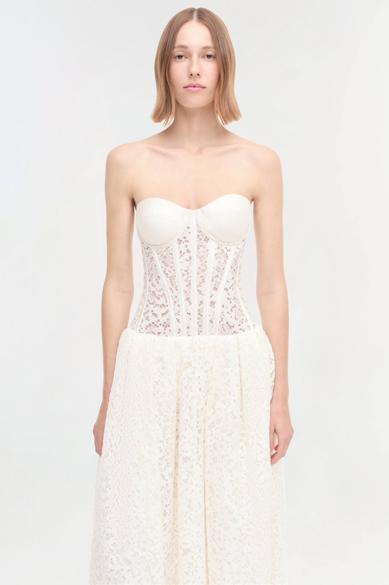 White strapless dress with sweetheart neckline, embellished corset bodice, and lace skirt.