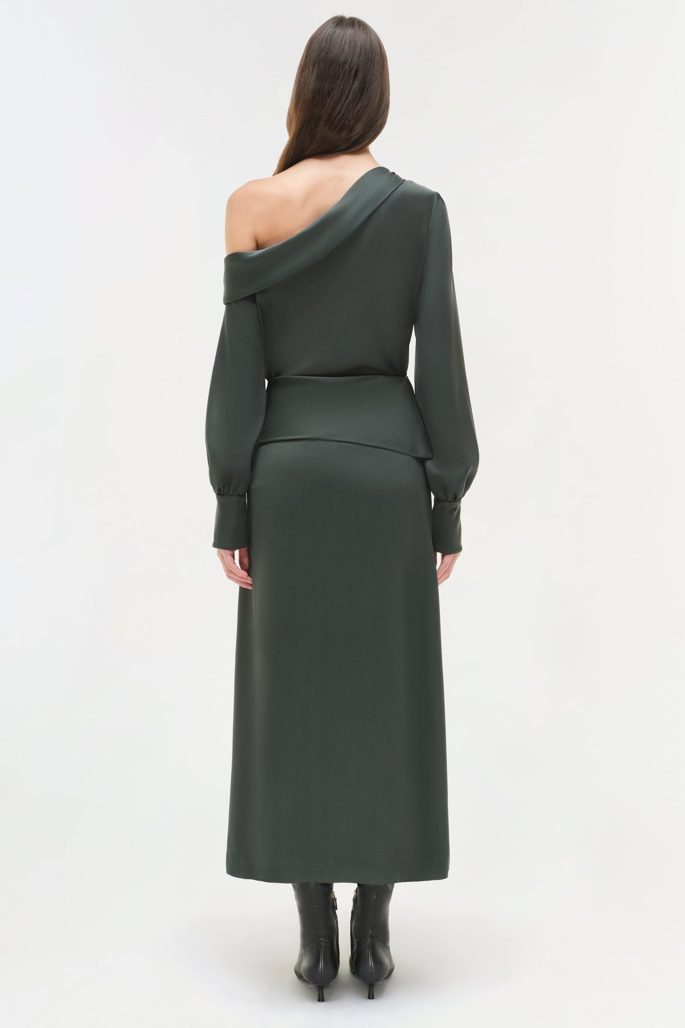 Woman wearing dark green satin midi skirt with matching off-shoulder long-sleeve top, shown from back.