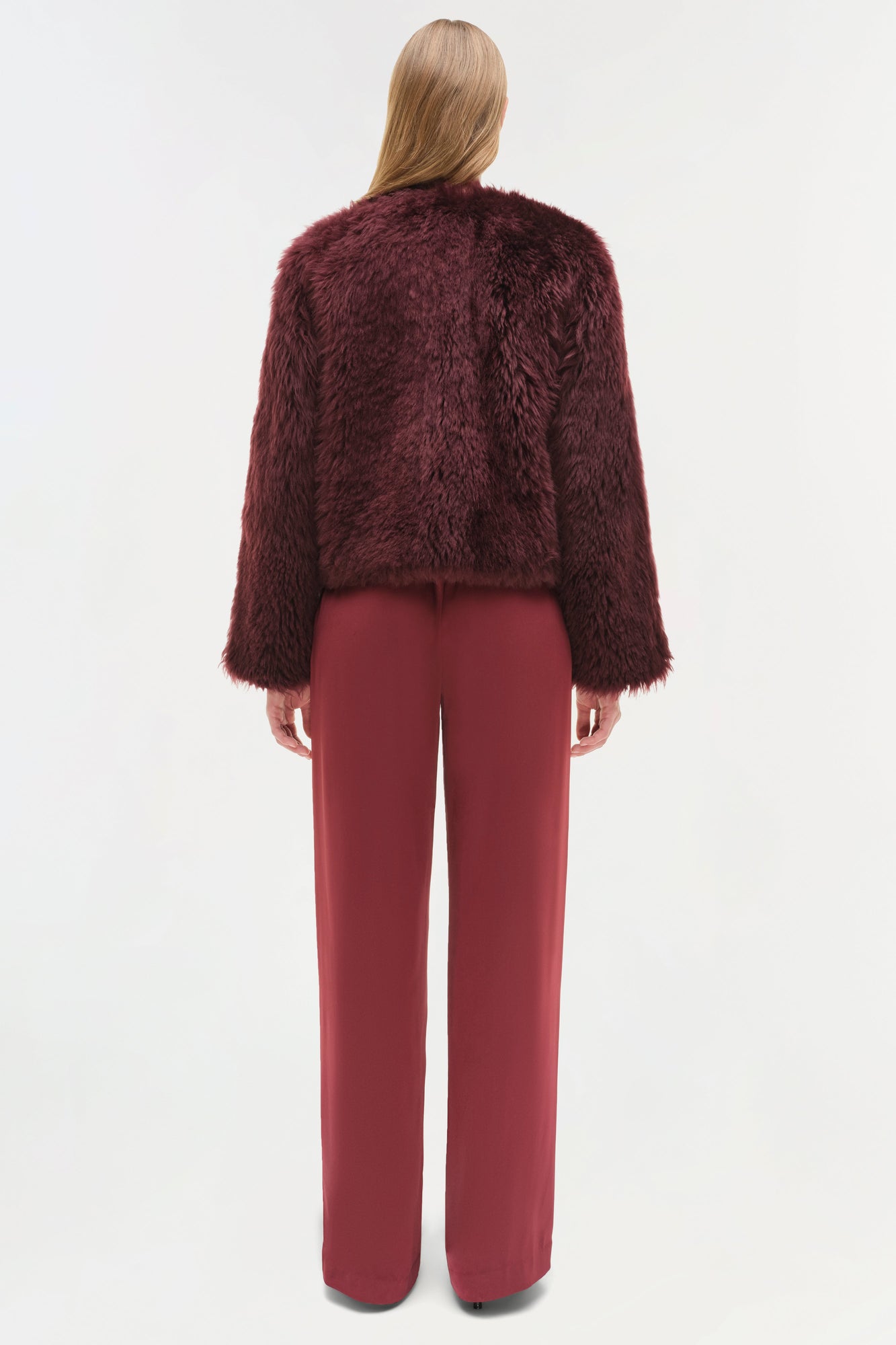 Burgundy shearling jacket with fuzzy texture and cropped fit, shown from back on model wearing matching pants.