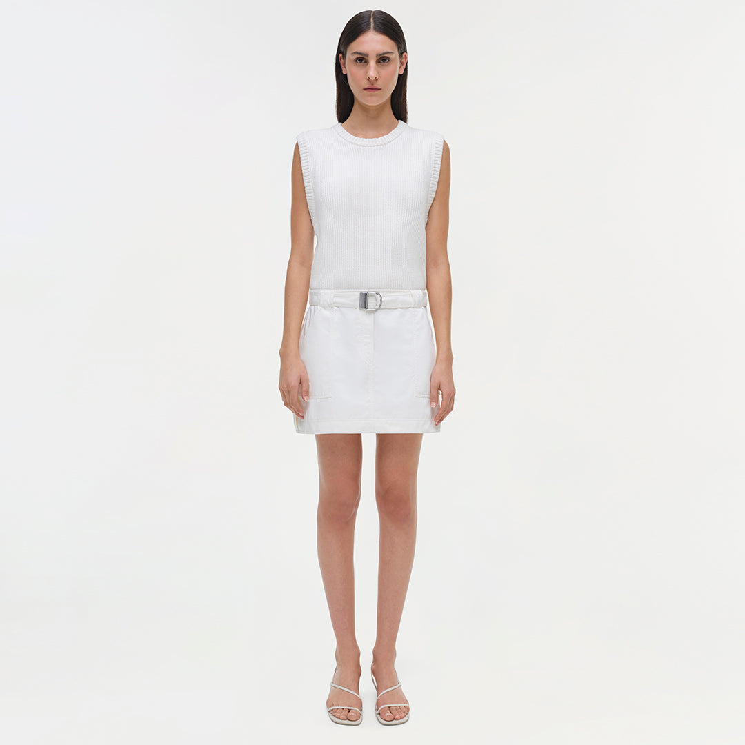 White sleeveless ribbed dress with belt at waist and knee-length skirt.
