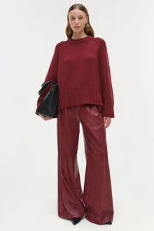 Burgundy crewneck cashmere sweater with ribbed hem and cuffs worn with matching wide-leg pants.
