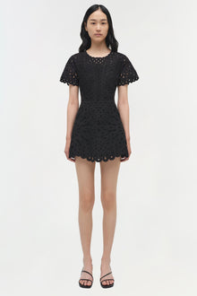 Black mini dress with intricate cutout embroidery throughout, short scalloped sleeves, and scalloped hem.
