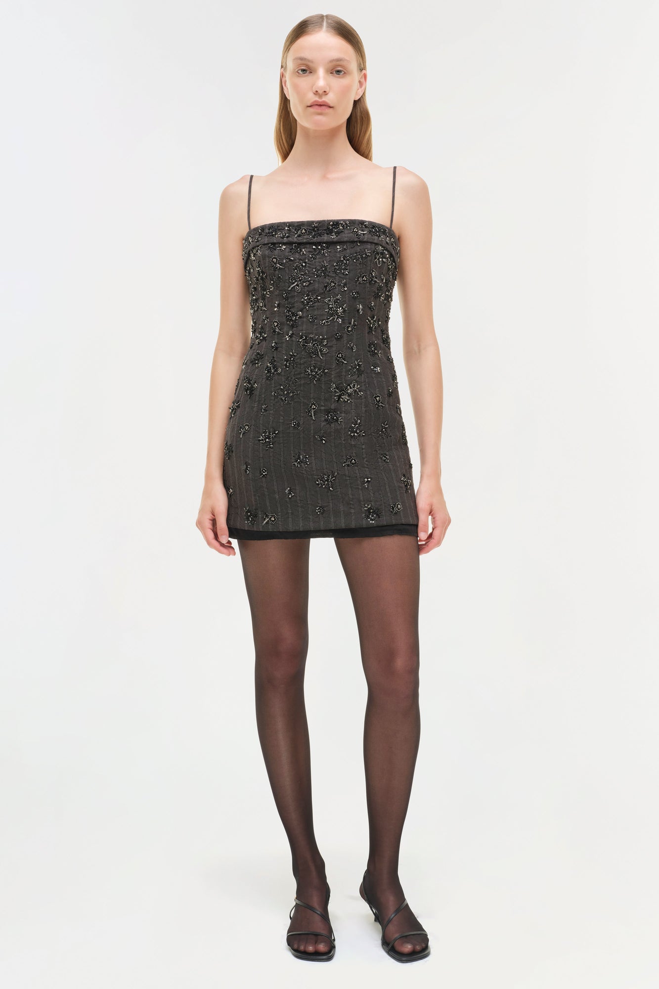 Black mini dress with silver beaded embellishments, thin straps, and straight neckline.