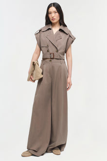 Woman wearing a taupe sleeveless button-front top with wide collar and belted waist, paired with wide-leg trousers.