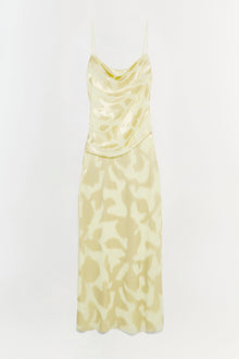 Pale yellow slip gown with cowl neckline, thin straps, and abstract patterned skirt.