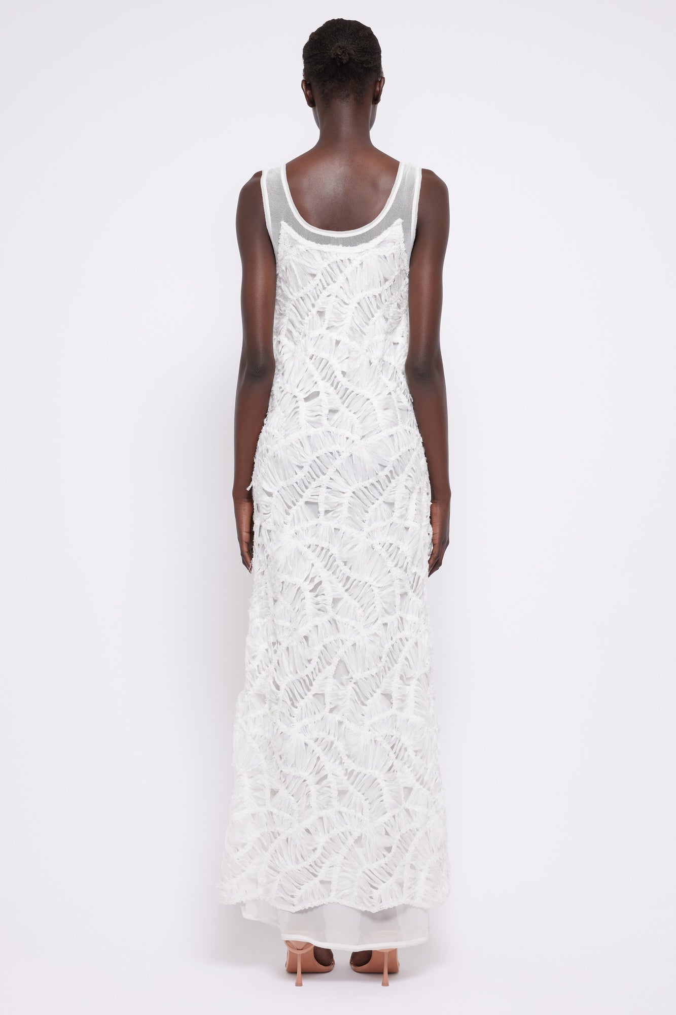 White sleeveless maxi dress with textured fringe detailing throughout, shown from back view on model.