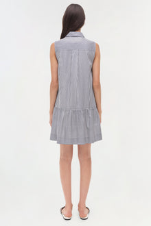 Woman wearing a sleeveless blue and white striped shirt dress with a collared neckline and dropped waist.