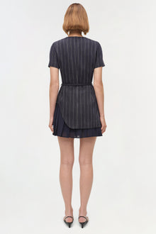 Navy pinstriped mini dress with short sleeves, belt at waist, and layered skirt hem, shown on model from back.