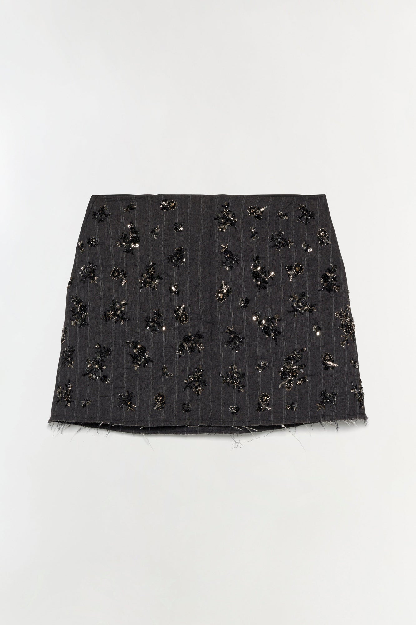 Black mini skirt with all-over beaded and sequin embellishments, frayed hem, vertical pinstripe pattern.