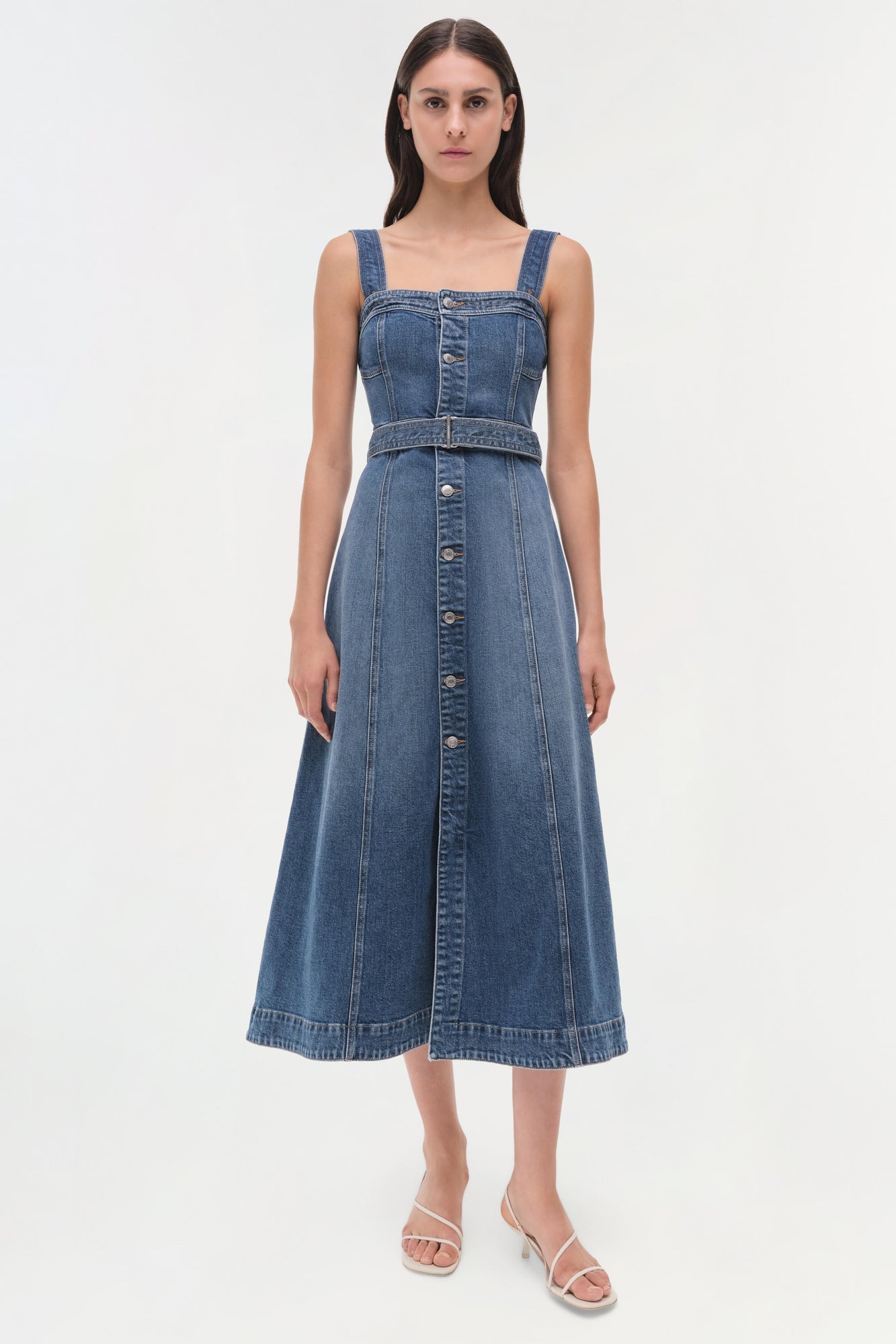 Blue denim sleeveless dress with square neckline, button front, and belted waist on model.