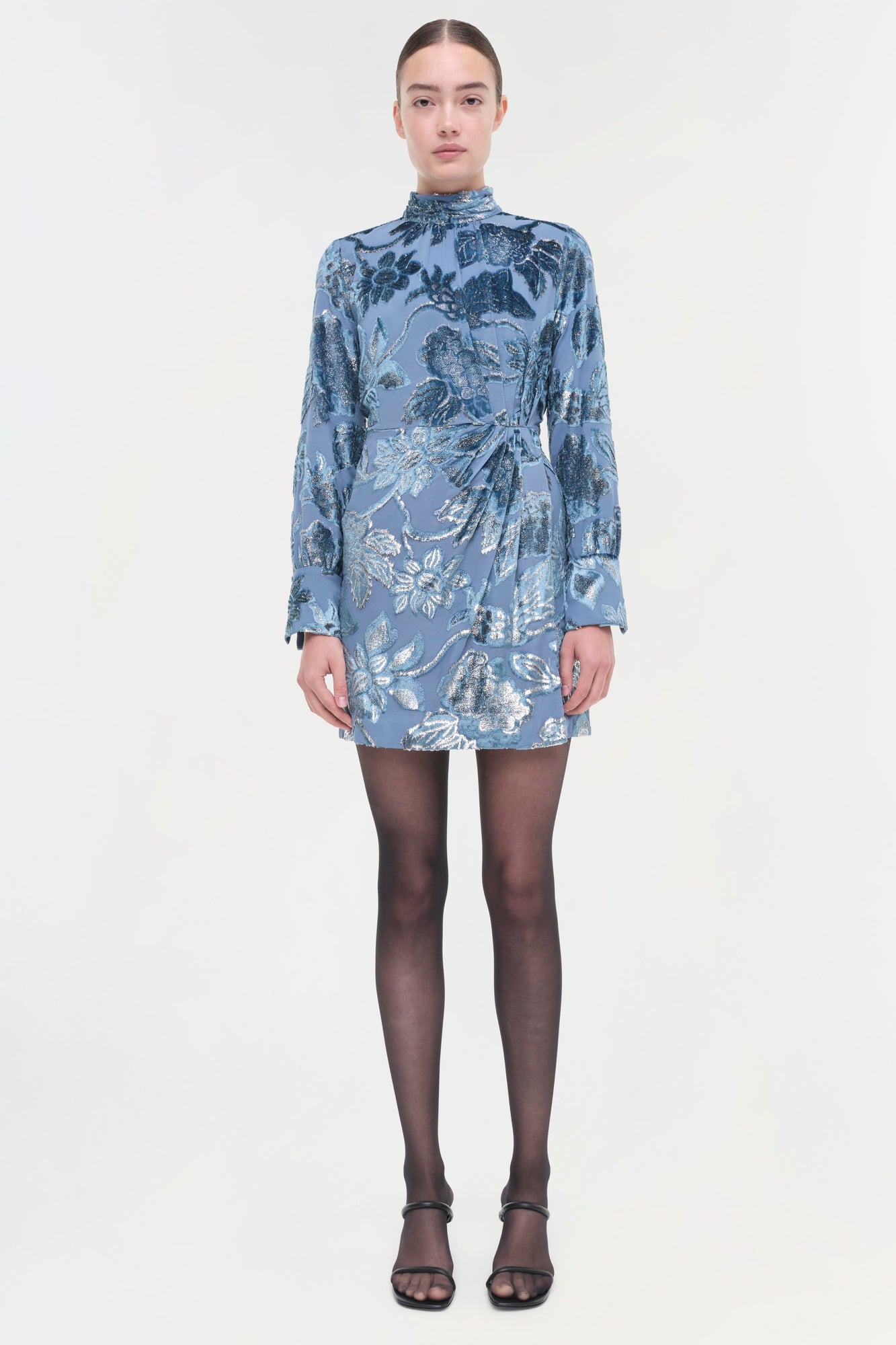 Blue floral wrap dress with long sleeves and high neckline, worn with black tights and strappy sandals.