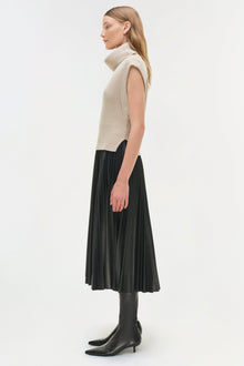 Black pleated midi skirt with high waist, paired with cream sleeveless turtleneck sweater and black ankle boots.