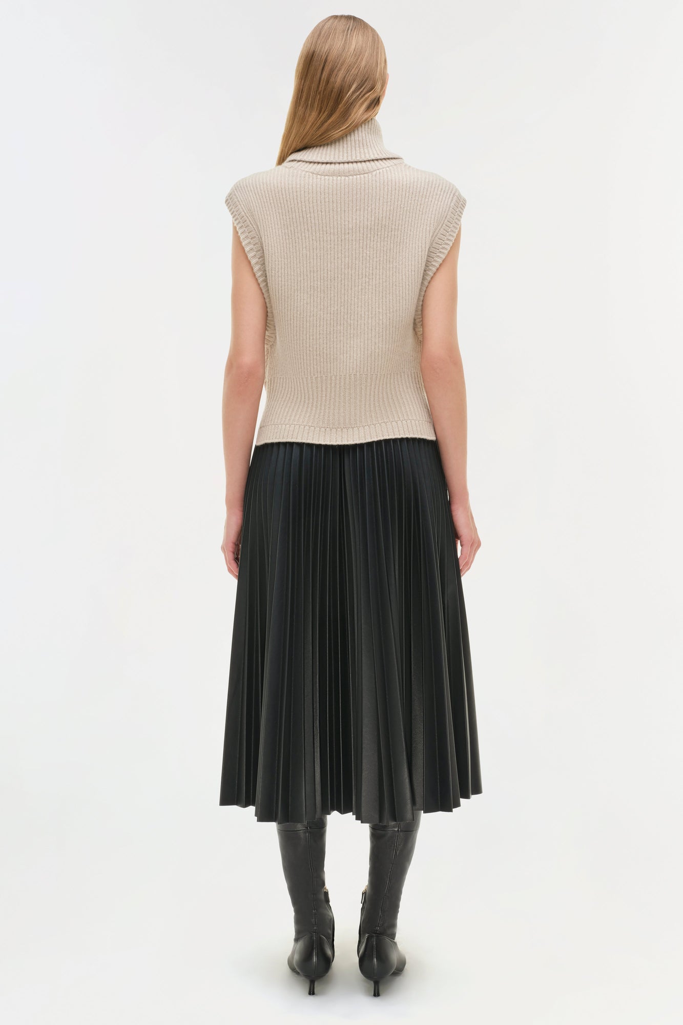 Black pleated midi skirt with high waist, paired with cream sleeveless ribbed turtleneck, styled with black boots.