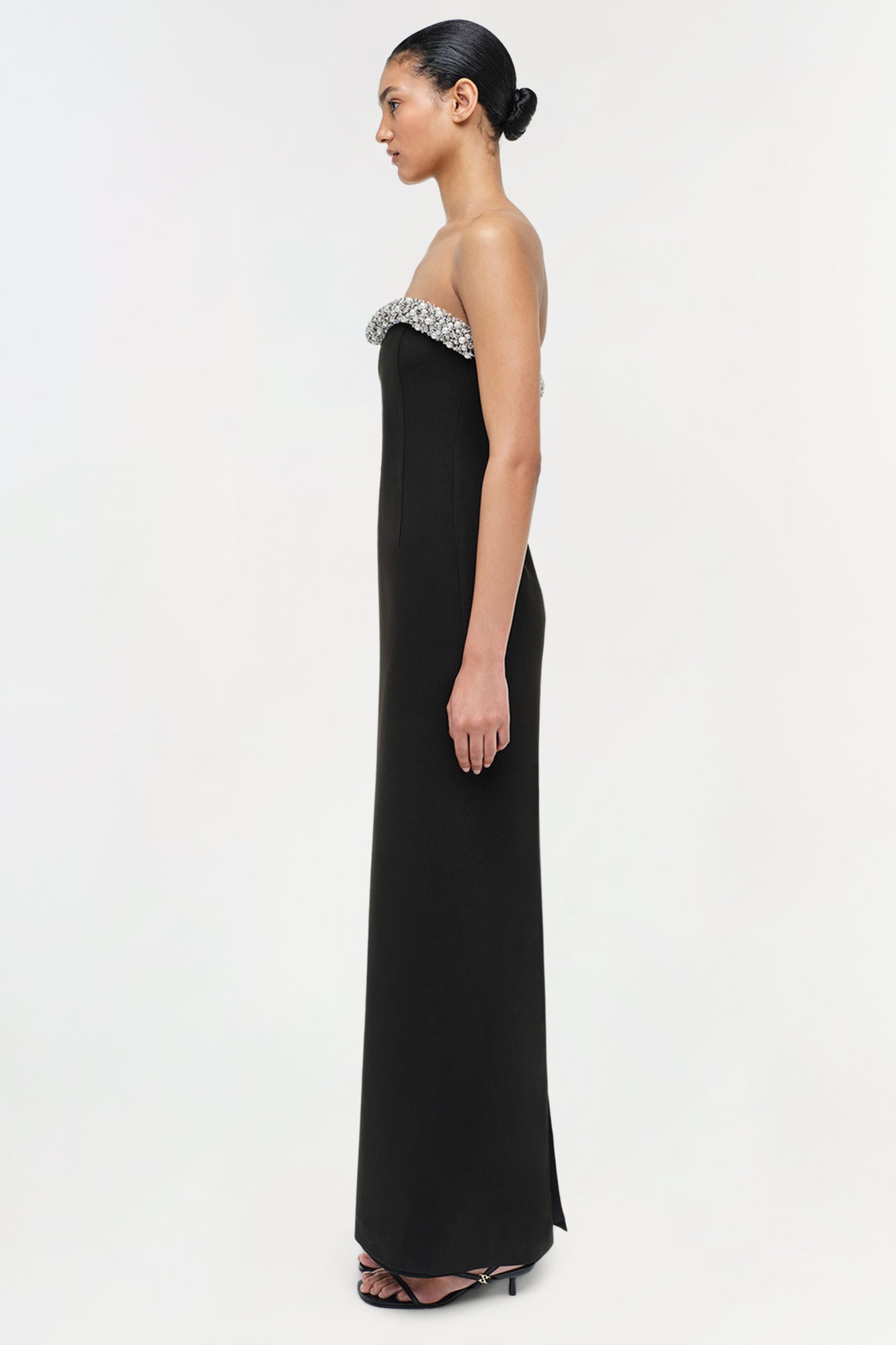 Black strapless floor-length gown with crystal beaded neckline detail, shown on model in profile view.
