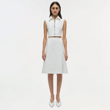 White sleeveless collared top with front zip closure and brown belt detail at waist.