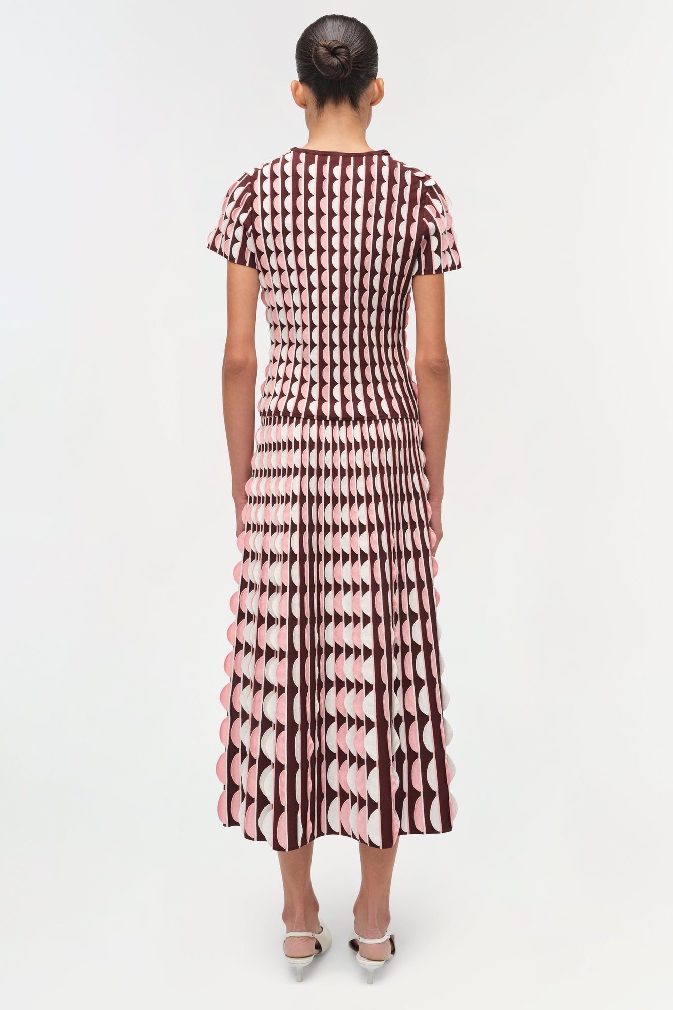 Burgundy and pink knit midi skirt with scalloped edge details and geometric pattern, shown from back view.