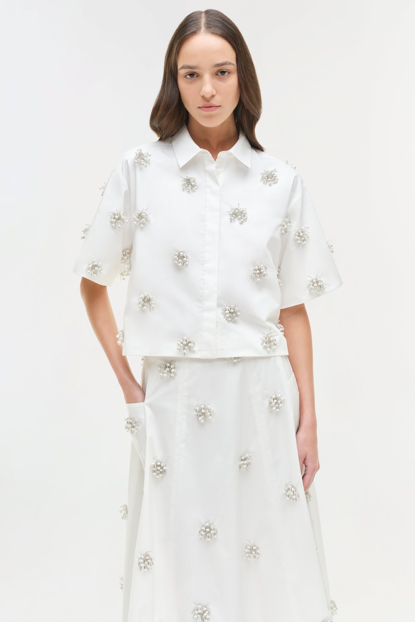White camp shirt with silver beaded floral embellishments scattered throughout, featuring a collared neckline and short sleev