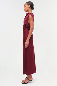 Burgundy sleeveless satin midi dress with ruched side detailing, shown on model from side profile.