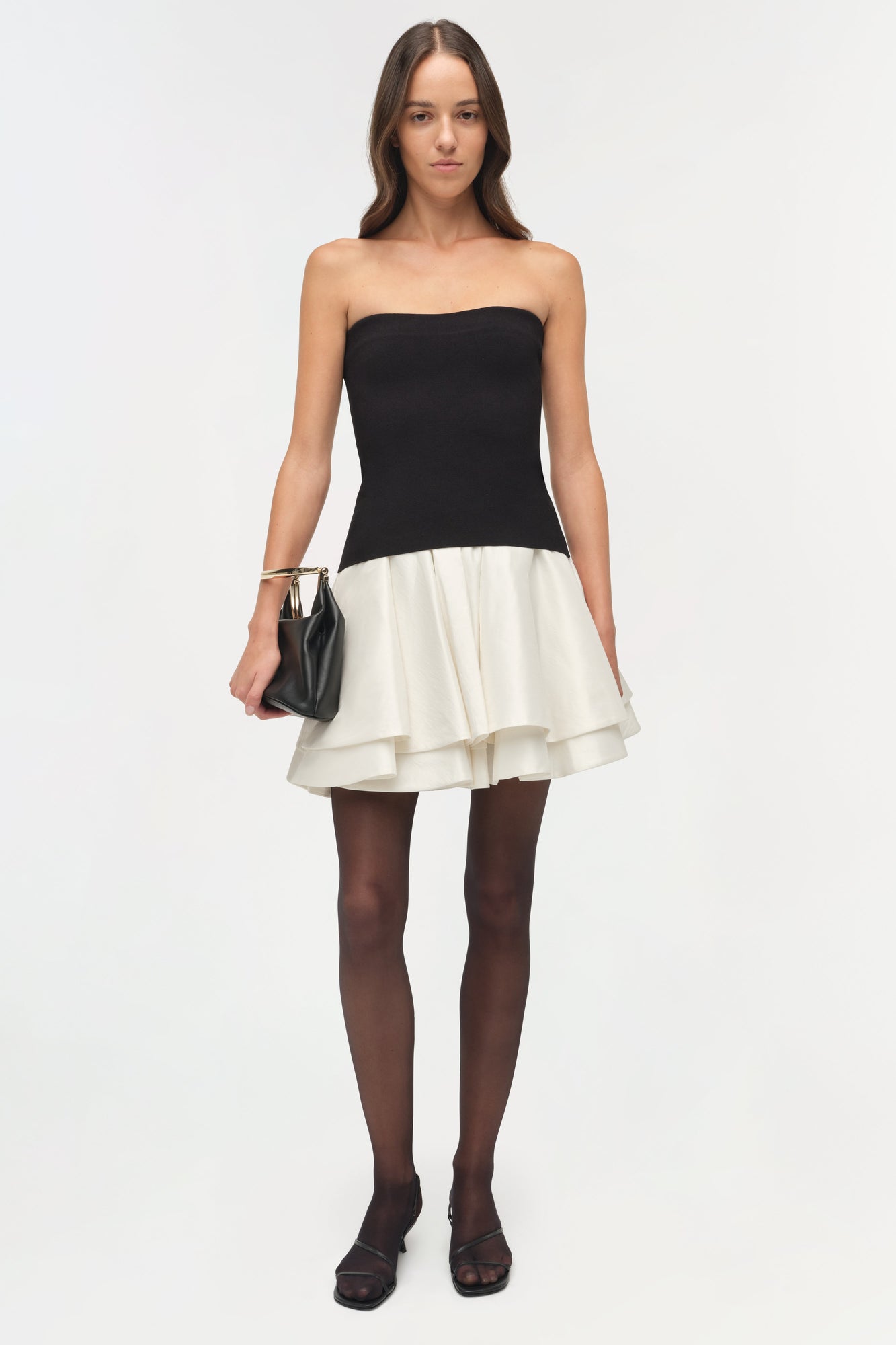 Black and cream strapless mini dress with tiered skirt, paired with brown tights and black platform sandals.