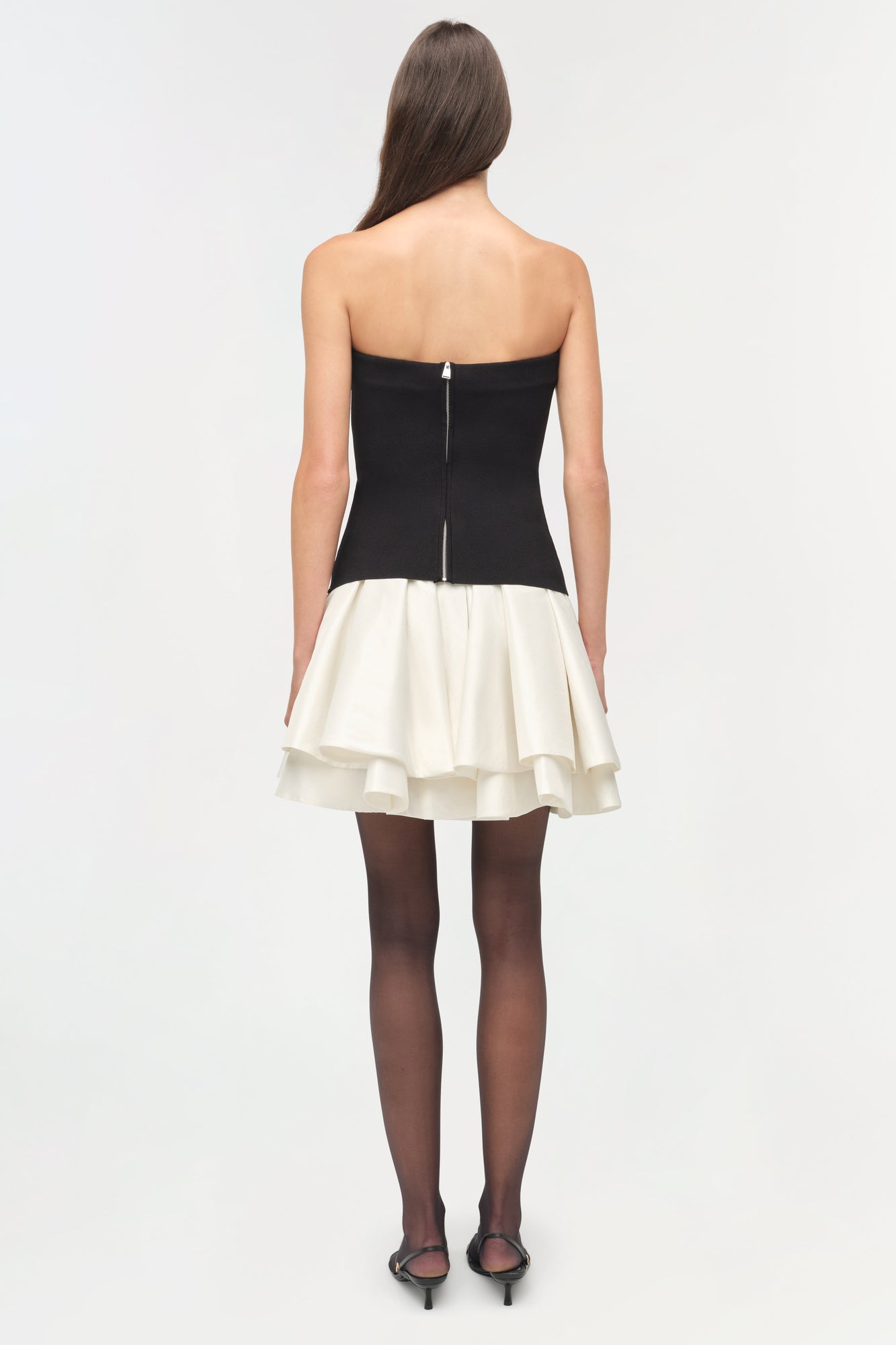 Black strapless knit bodice with cream tiered taffeta skirt, shown from back with dark tights and heels.