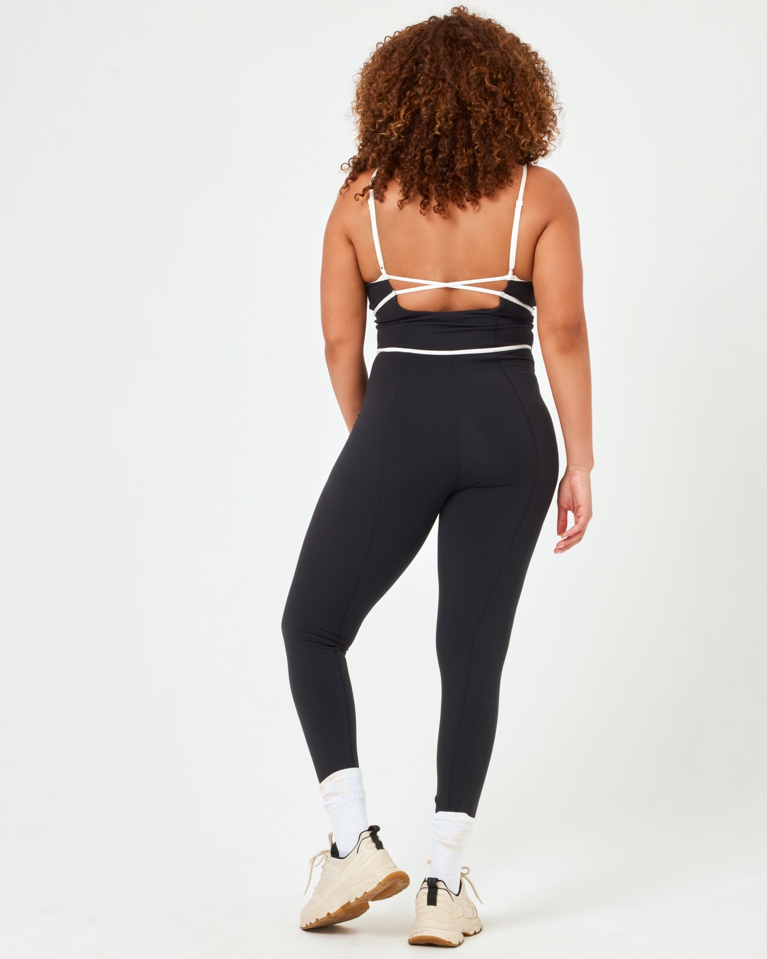 Back view of model wearing the Ace Jumpsuit in black-cream in XL showing the open back with cream piping detail.