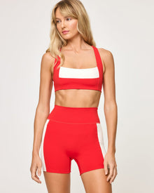 Close-up front view from the knees up of the LSPACE Uppercut Bra in flame-cream on a model, showing the square neckline with cream trim detail, paired with the matching flame-cream high-rise active shorts.