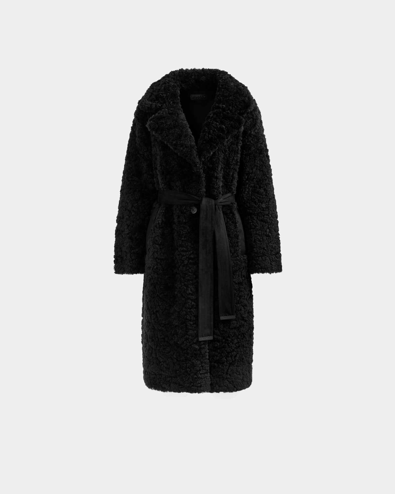 The Rudsak ANNABELLE FSU - L125512 Black is a long black sherpa teddy trench coat with wide lapels and a matching fabric belt, shown against a plain light background.