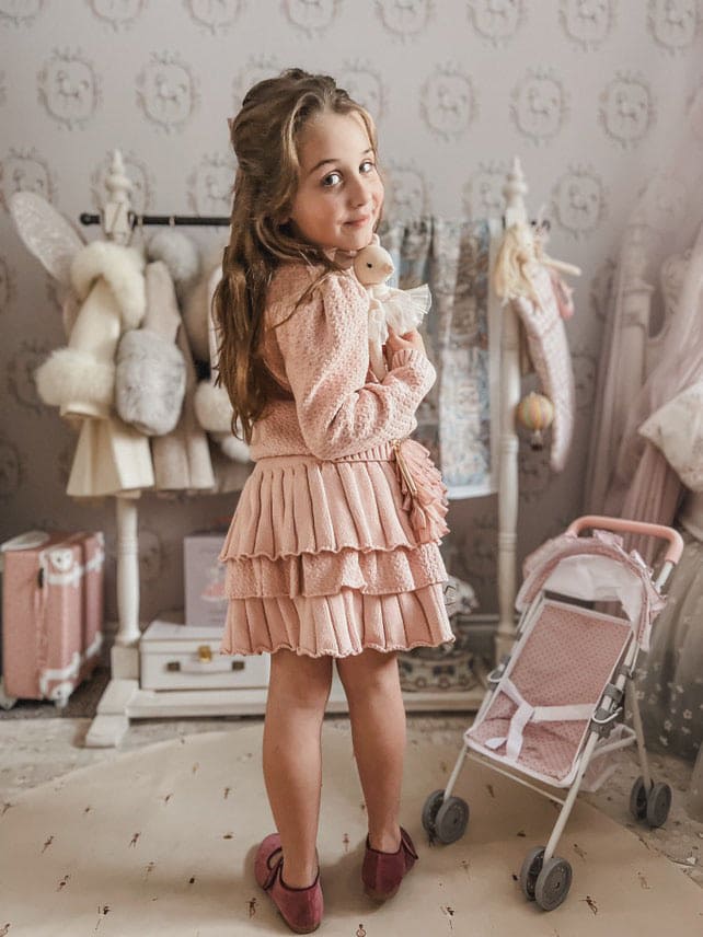 Girl wearing Julie pink knit cotton top and skirt set indoors, soft feminine styling