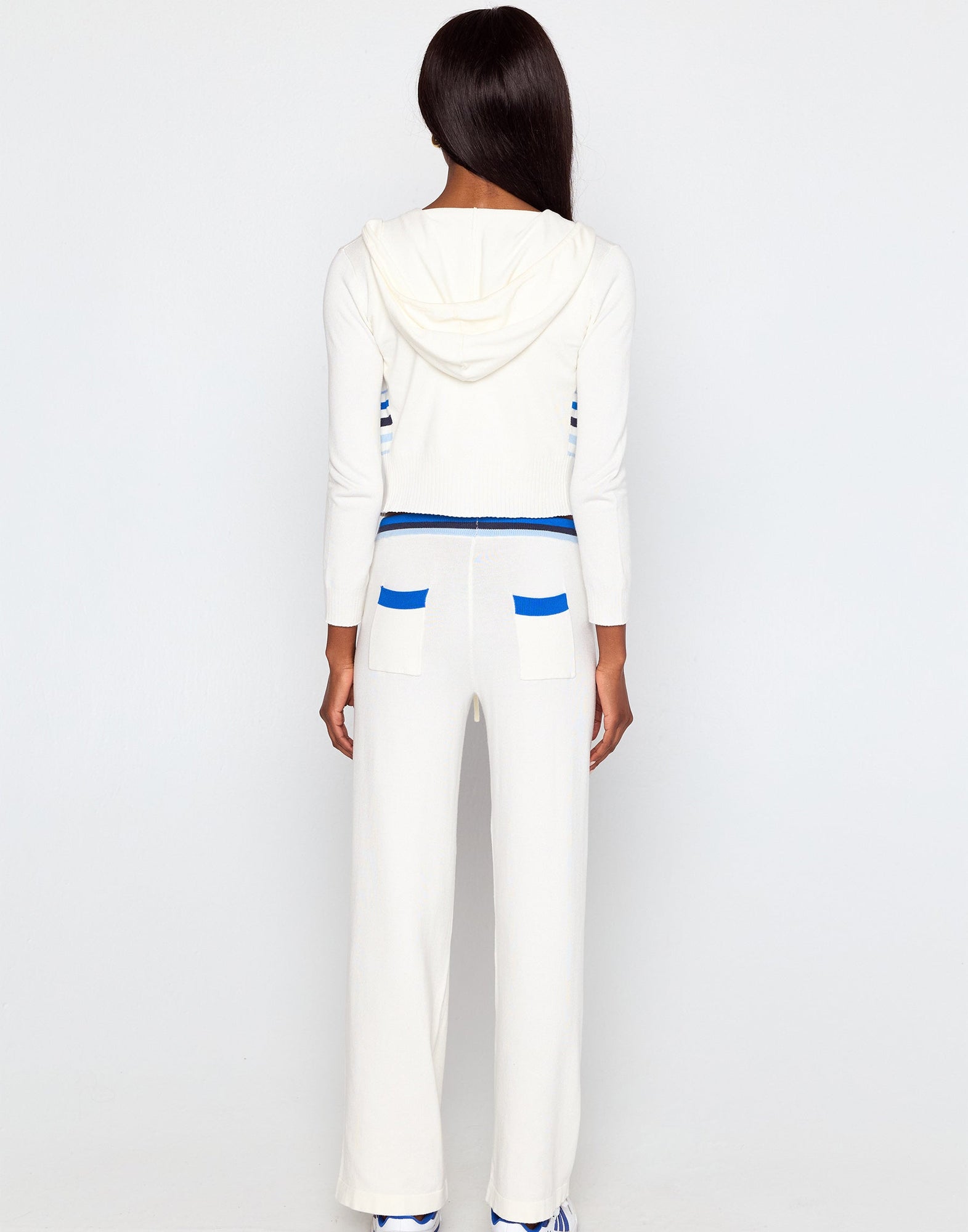 Person wearing a white outfit with blue accents on a plain background