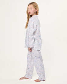 The Kid's Twill Pajama Set in Baking Spirits Bright features white long-sleeve button-up top and long pants with a colorful print of various small household and travel items.