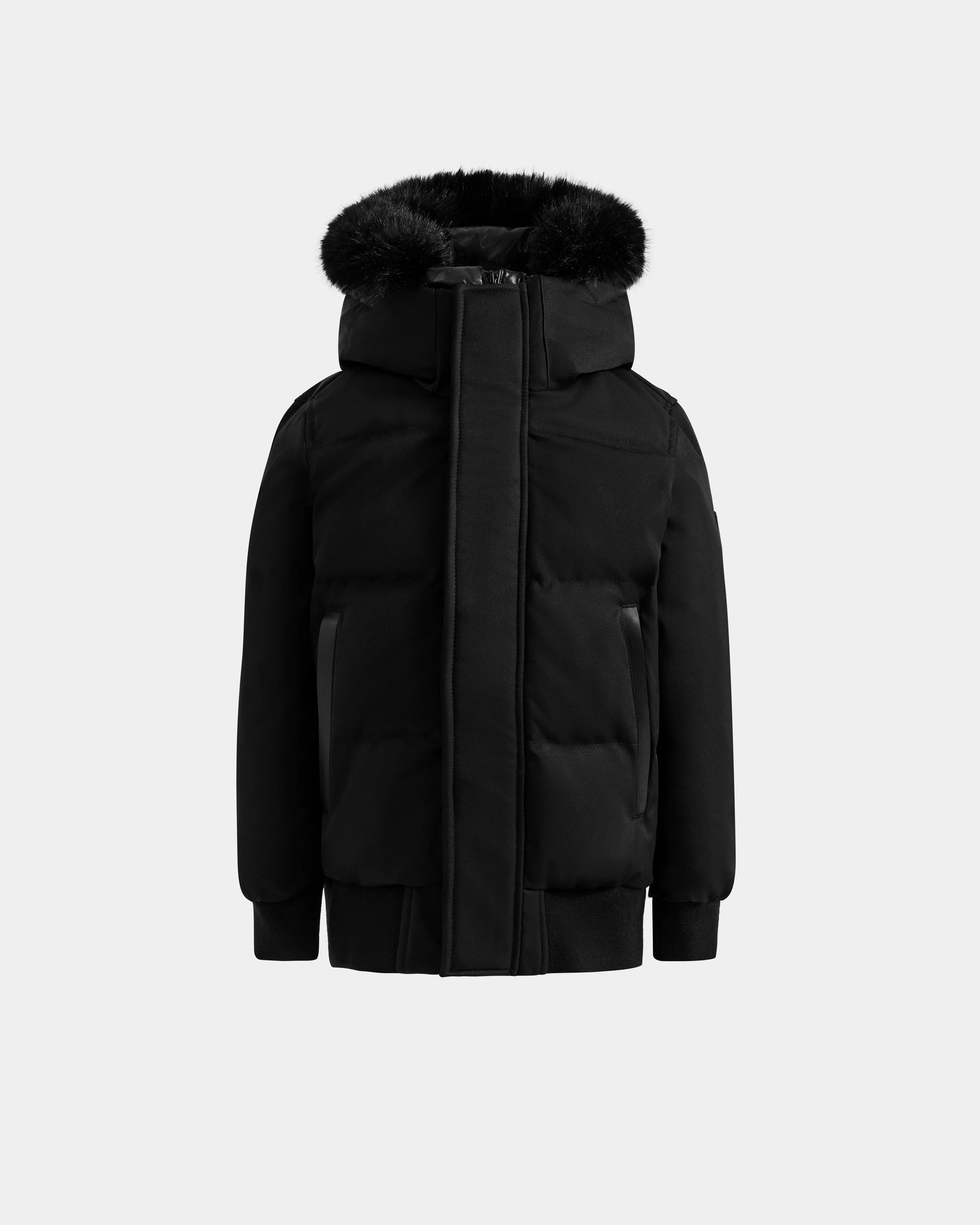 The Rudsak DALLAS K - K125501 Black is a black puffer jacket featuring a hood with black faux fur trim, a front zipper concealed by a flap, and ribbed cuffs and hem, shown against a plain light gray background.