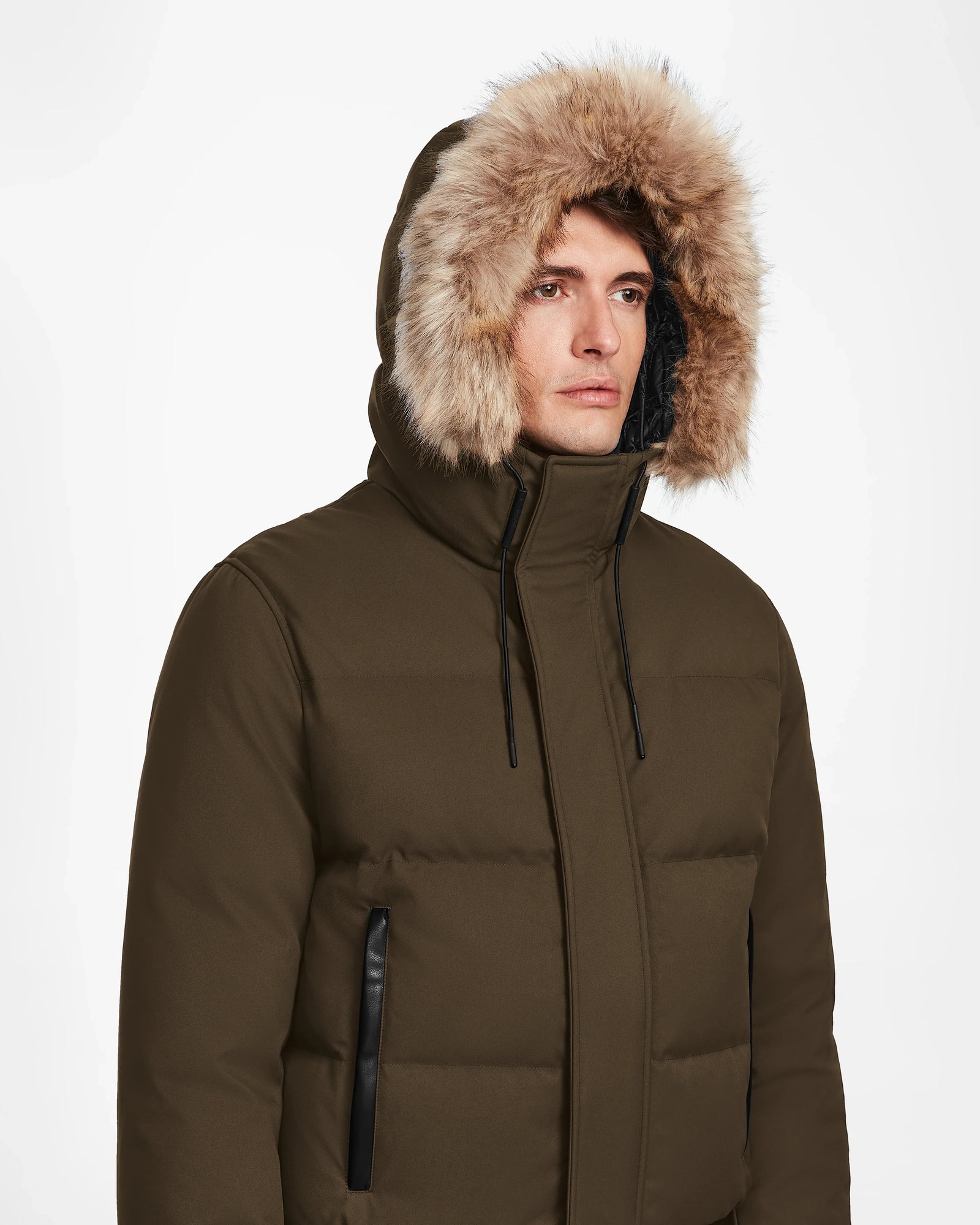 A person wears the Rudsak DALLAS - M122501 Army men's quilted down bomber with a fur-lined hood, facing forward with a neutral expression against a plain white background.
