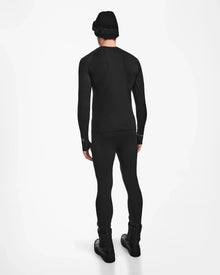 A person showcases the back view of the Rudsak FRANC - 6524541 Black ski underlayer outfit against a plain white background, wearing a black beanie, long-sleeve top, leggings, and boots.