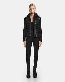 A woman faces forward wearing the RUDSAK MABS - 8122020 BLACK RDS-certified down puffer vest over a black long-sleeve outfit and lace-up boots, set against a plain white background.