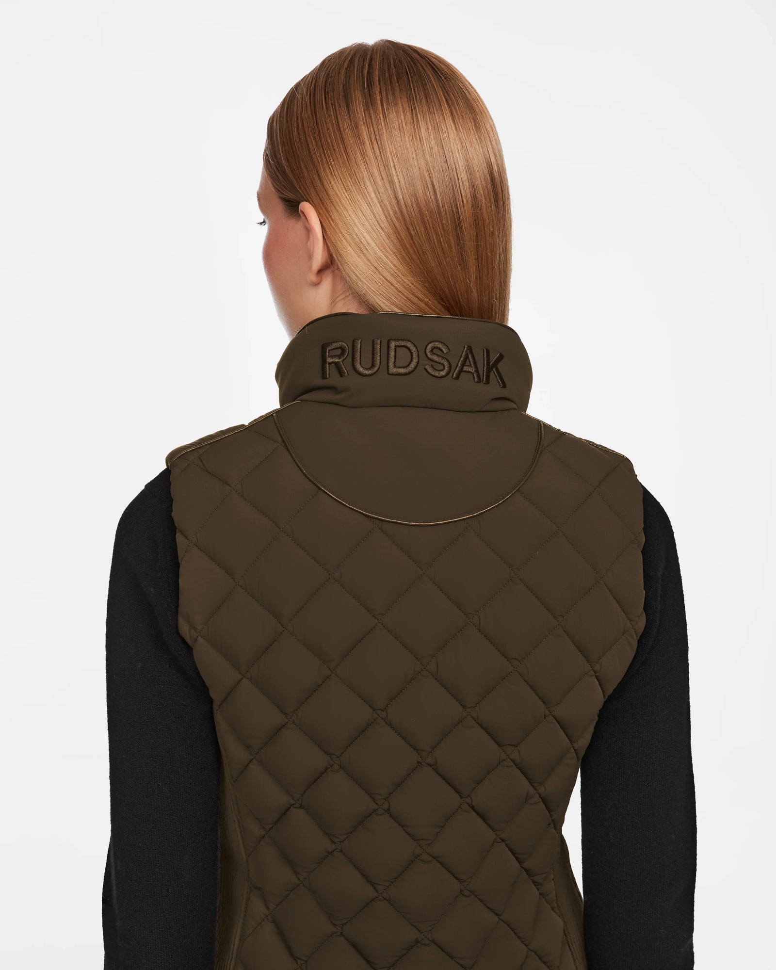 A person with straight, light brown hair is seen from behind wearing the Rudsak MATILDA - L124504 Army quilted vest with embroidered collar—an ideal transitional layer over a long-sleeve black shirt.